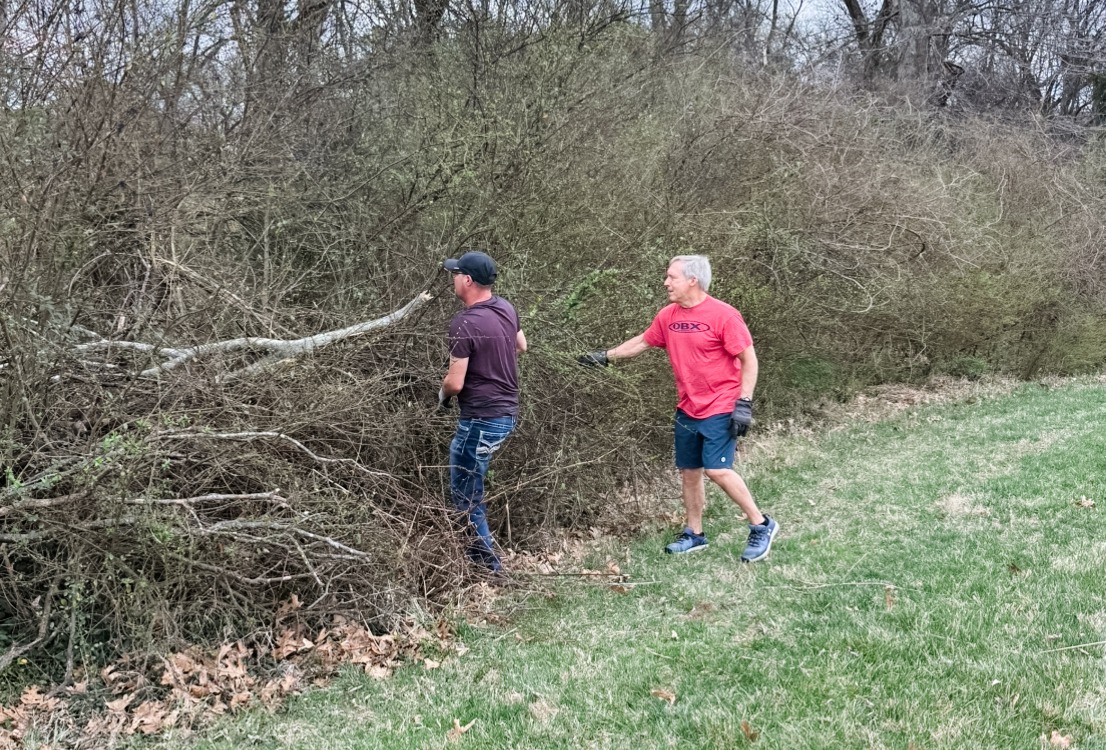 Rob Reyburn and a neighbor clearing storm-damaged trees from a shared neighborhood green space.