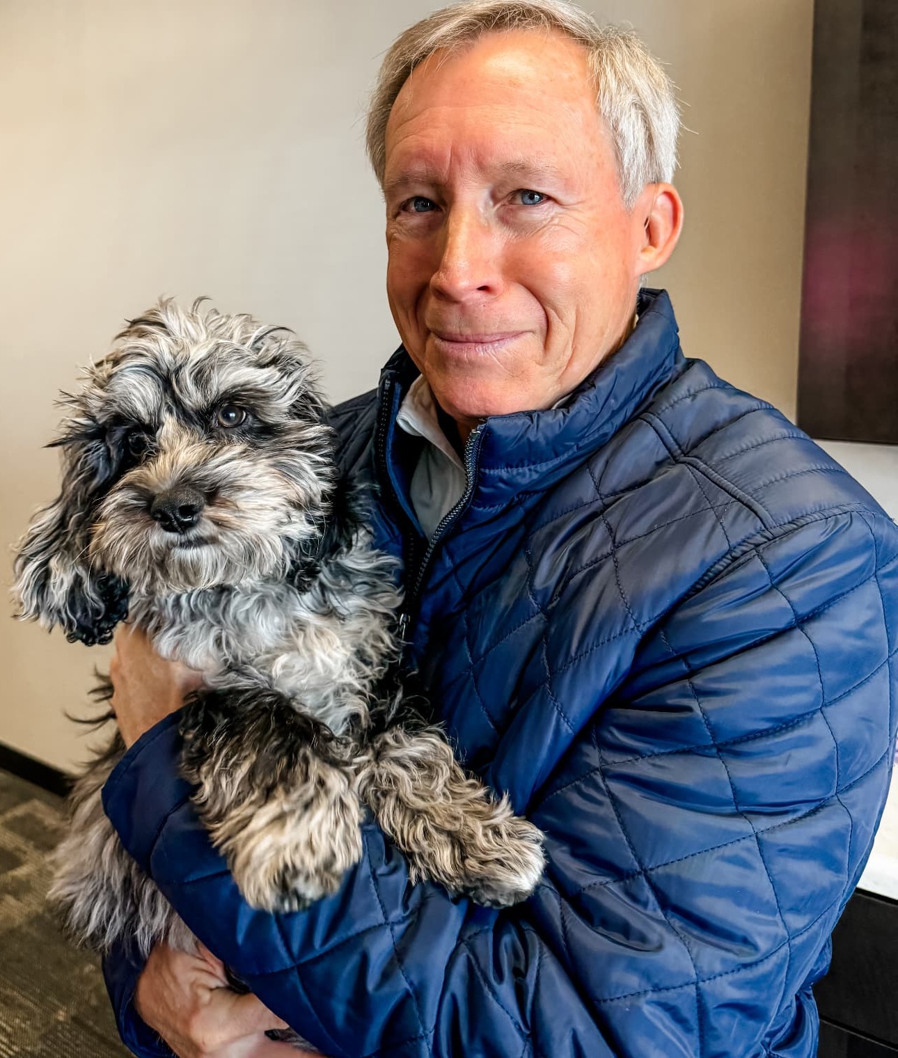 Rob Reyburn holding a small gray and black dog